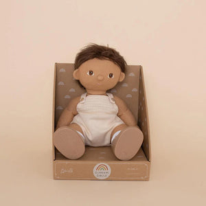 A DINKUM DOLL from OLLI ELLA USA features soft brown hair and comes dressed in a white knit romper paired with brown shoes. This charming doll has an embroidered face with brown eyes, a small nose, and a gentle smile. Its posable body makes it perfect for imaginative playtime, and it is posed standing upright.