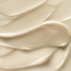 Close-up view of smooth, creamy, light beige substance spread in swirls, resembling the luxurious ELEMIS - PRO-COLLAGEN VITALITY EYE CREAM. The glossy surface showcases its rich and firming consistency, perfect for revitalizing delicate skin.