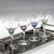 The ZODAX MARTINI COCKTAIL OPTIC GLASS is a clear glass goblet with a long stem and a wide, round bowl accented by a decorative blue detail near the base of the bowl. With a capacity of 208.5 ml, it is empty and placed against a plain white background.