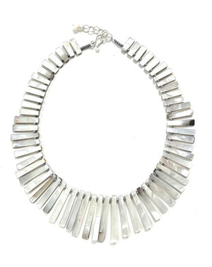 The ANN LIGHTFOOT - REVERSIBLE SHELL RAS DU COU FAN NECKLACE by ANN LIGHTFOOT features multiple rectangular shell pieces, arranged in a graduated design. These shells display iridescent shades of brown, gray, and hints of pink, creating a harmonious and elegant look.