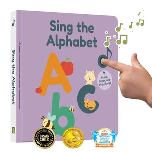 A child's hand presses a musical note button on the cover of a colorful ABC Sound Book titled "CALI'S BOOKS - SING THE ALPHABET NURSERY RHYMES." Featuring cute animal characters and alphabet letters, this award-winning toddler learning toy proudly displays badges for Brain Child and National Parenting Awards at the bottom.