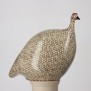 A ceramic figurine of a bird stands against a white background. With its rounded body, speckled black and white pattern, and small red crest on its head, it evokes the charm of French guinea hens. Crafted from handmade pottery in a local ceramic workshop, LES CERAMIQUES DE LUSSAN - LARGE CERAMIC FRENCH GUINEA IN WHITE SPOTTED BLACK by LES CERAMIQUES DE LUSSAN is truly unique.