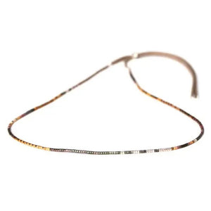 Introducing the ORO NECKLACE by JULIE ROFMAN JEWELRY, a sophisticated piece featuring an array of small, square beads in shimmering shades of gold, silver, and copper. Designed with adjustable sizing for a perfect fit, this necklace is elegantly showcased on a plain white background in a circular formation to highlight its refined simplicity.