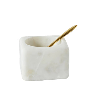 The CREATIVE COOP MARBLE BOWL WITH BRASS SPOON features a square white marble salt cellar with a smooth finish, serving as both elegant table decor and a functional kitchen accessory. The brass spoon adds sophistication to the minimalist yet luxurious design.