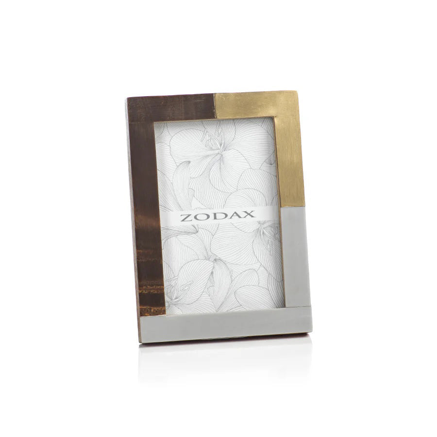 The ZODAX CAPE TOWN PHOTO FRAME - 4X6 features a modern rectangular design with brown wood, gold, and silver metal sections. This upright glass frame displays floral line art and the &quot;ZODAX&quot; logo.