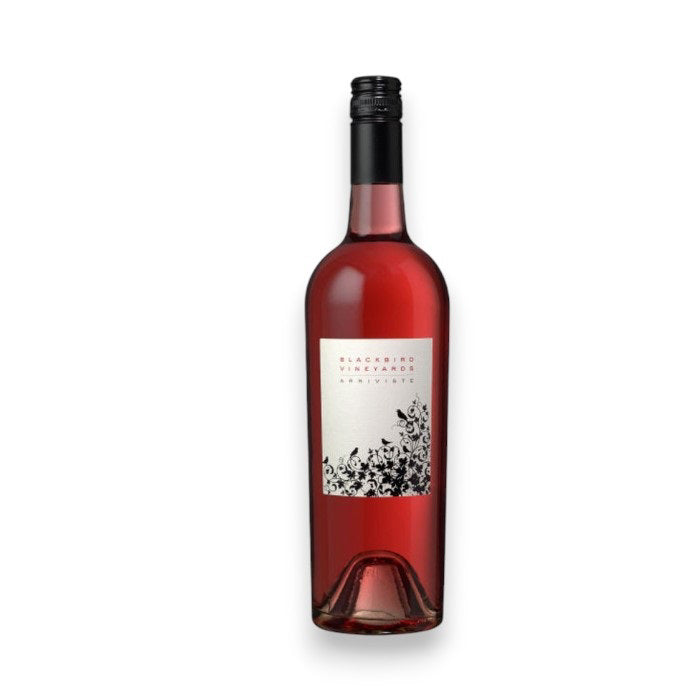 A bottle of BLACKBIRD &#39;ARRIVISTE&#39; ROSÉ 2024 by WINE: ADVINTAGE, featuring a black screw cap and white label with black floral designs, is showcased against a plain white background. The label highlights Merlot from Napa Valley.
