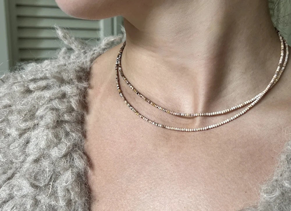 The ANN LIGHTFOOT - Mookite Ombre Ras du Cou Necklace features small, round brown and pink beads with a sterling silver clasp, shown in a circular shape on a white background.