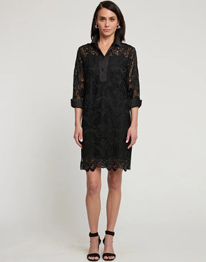 A person stands against a plain background wearing the Aileen Black Lace Dress by Hinson Wu, featuring knee-length black lace with 3/4 sleeves and button details. Paired elegantly with black high-heeled sandals, this outfit exudes a formal style perfect for the holiday season.