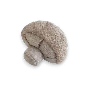 A small, plush button mushroom toy from LAMBWOLF COLLECTIVE. The cap is covered in a fuzzy, textured fabric, while the stem and gills are made from a smoother material in a matching beige color. Designed by LAMBWOLF COLLECTIVE to look cute and cuddly, this washable pet toy is perfect for both playtime and snuggles.