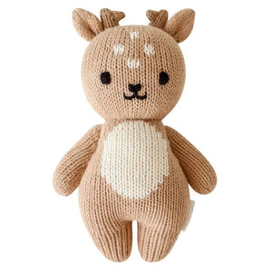 The CUDDLE + KIND - HANDMADE BABY FAWN by CUDDLE & KIND is a charming hand-knit baby fawn plush toy. It resembles a brown deer with two small antlers, round ears, and a petite white tail. The toy stands upright on its legs, facing backwards, highlighting its intricate stitching and soft texture—ideal for fair trade income newborn gifts.