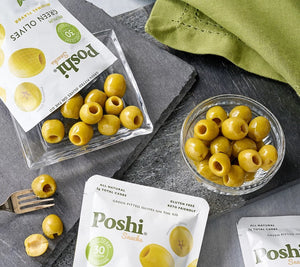 A white resealable pouch of POSHI - OLIVES Premium Green Olives in original flavor. The package highlights "All-Natural," "Gluten-Free," "Keto Friendly," and "30 Calories per Bag." The front features images of ready-to-eat, non-GMO certified, liquid-free green olives. 1.1 oz (30 g).