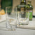 A clear, cylindrical NEGRONI HAMMERED DOUBLE OLD FASHIONED GLASS by ZODAX with a slightly textured surface and a thin gold rim at the top, boasting a capacity of 347 ml. The glass is empty and positioned against a plain white background.