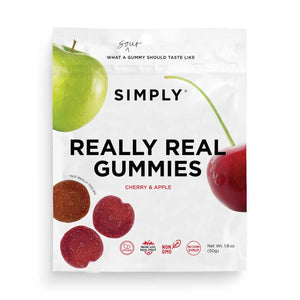 A white package labeled "SIMPLY GUM - REALLY REAL SOUR APPLE AND CHERRY GUMMIES 1.8OZ" from the brand SIMPLY GUM contains cherry and apple flavored gummies made with real fruit. The packaging features images of a green apple and a red cherry. The gummies are advertised as sour, non-GMO, and having no corn syrup or artificial flavors. Net weight is 1.8 oz (50g).