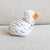 The KNOTTY PAWZ Agnes White Duck Squeaky Rope Toy features a knitted design with a white body, orange beak, and ribbon embellishment. Set on light gray fabric, this toy appeals to eco-conscious pet owners who prefer handmade products.