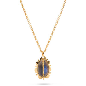 Introducing the CAPUCINE DE WULF - BLISS BLUE LABRADORITE NECKLACE by CAPUCINE DE WULF: a handcrafted gold necklace featuring an oval-shaped blue Labradorite gemstone set in a decorative 18K gold frame. The delicate chain has adjustable length links and is secured with a small clasp.