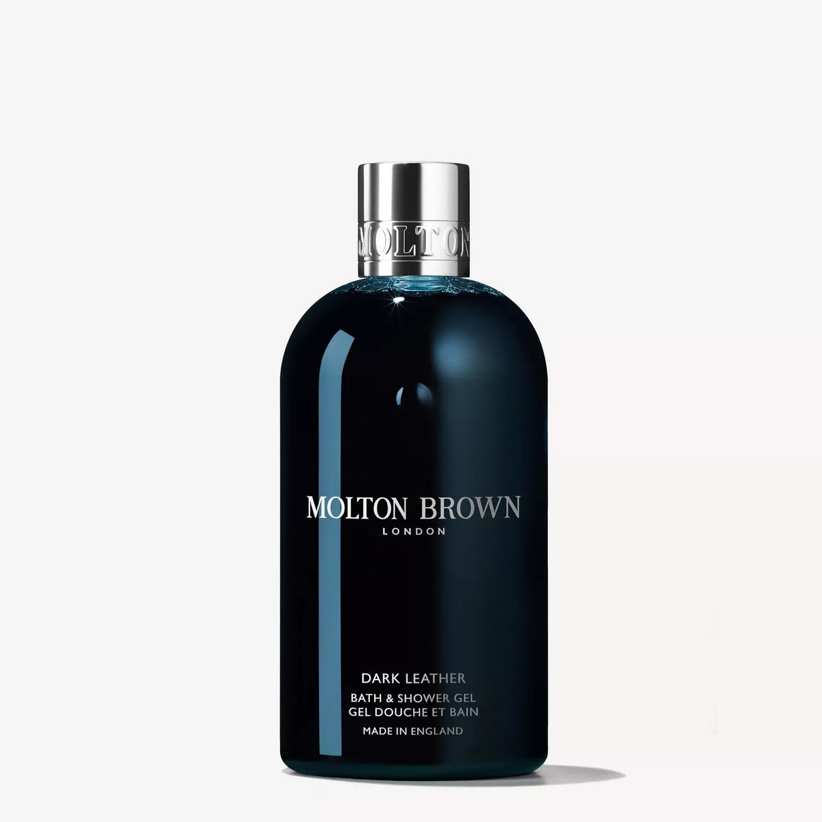 A dark blue bottle of MOLTON BROWN DARK LEATHER BATH AND SHOWER GEL with a silver cap stands upright on a white background, featuring white label text that hints at the smoke-tinged leather scent of this woody body wash.