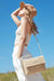 The MAR Y SOL - RHODES CROSSBODY CLUTCH from MAR Y SOL is a beige woven straw clutch bag featuring a tight, uniform weave that offers a natural, artisanal appearance. The simple yet elegant silhouette is adorned with delicate crochet detailing, making it perfect for both casual and semi-formal occasions.