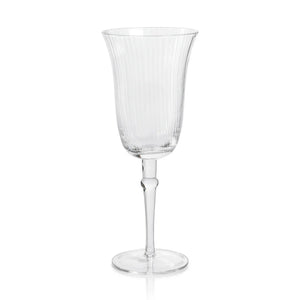 The JULIEN CLEAR OPTIC WINE GLASS by ZODAX is a clear, elegant 300 ml wine glass featuring a fluted bowl that rests on a slender stem with a circular base. Subtle vertical lines are etched into the bowl, enhancing its sophisticated design.