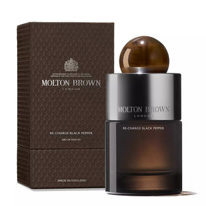 The MOLTON BROWN - RE-CHARGE BLACK PEPPER Eau de Parfum bottle is cylindrical and labeled with the brand's signature name. It features a glossy gradient from dark to light brown, topped with a spherical, marbled brown cap. This sleek and sophisticated design embodies the essence of dynamic sophistication.