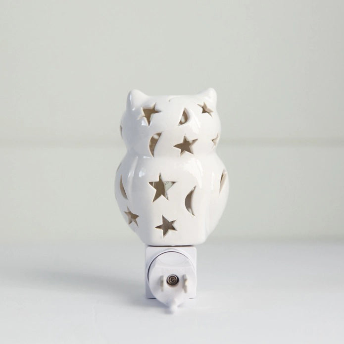 The OWL NIGHTLIGHT by LILY'S LIGHTS features a white ceramic owl design with cut-out star and moon patterns that allow light to shine through beautifully. Plugged into a white electrical base and set against a plain white background, this nightlight exemplifies quality craftsmanship, making it one of the most unique gifts.