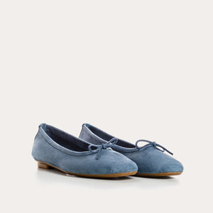The REQINS Harmony Suede Ballerina Flats in Blue Jean feature luxurious goat suede, a delicate front bow, and a low brown heel, displayed on a plain white background.