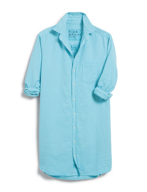 The FRANK & EILEEN Mary Classic Shirtdress in Famous Denim Ocean, a light blue, long-sleeved shirt, hangs against a white background. It features a single chest pocket, button-down front, and a classic collar. Reminiscent of an Italian Cotton Shirtdress, the sleeves are casually rolled up, and the slightly wrinkled texture gives it a relaxed look.