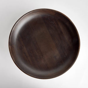 The BOWIE FOOTED BOWL by NAPA HOME AND GARDEN stands against a plain white background. Crafted from dark brown mango wood, its wide, shallow basin features smooth, curved edges and a polished finish that highlight the contemporary design's craftsmanship. The bowl rests on a solid, rounded base providing stability.