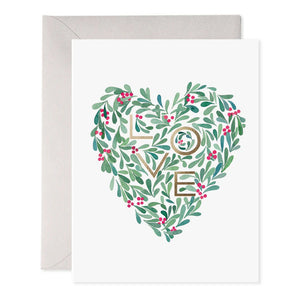 The HOLLY HEART HOLIDAY CARD by E.FRANCES PAPER showcases a heart-shaped design of green leaves and red berries on luxurious paper, reminiscent of a watercolor painting, and comes with an accompanying envelope. The bottom features the website information and a logo.