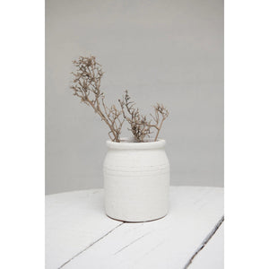 The DISTRESSED TERRACOTTA CROCK by CREATIVE COOP is a rustic, off-white earthenware pot with a cylindrical shape and slightly flared rim, featuring a textured finish. This charming piece adds timeless elegance to any home décor.