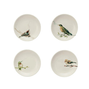 The BIRD CURIO DISH by CREATIVE COOP features a ceramic rectangular dish and four bowls with bird illustrations on parchment paper, complemented by a stoneware dish next to seven green tomatillos with husks for a rustic composition.