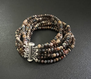 The ANN LIGHTFOOT Eight Strand Faceted 4mm Pietersite Bracelet showcases multiple strands of small, faceted rondelles in an array of brown and black shades. It is designed in a coiled circular form with a rectangular stainless steel clasp.