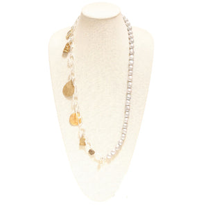 A BITTERSWEET DESIGNS - MIXED BLESSINGS SILVER AND PEARL NECKLACE displayed on a white mannequin bust. Handmade by artisans, it features a mix of clear beads, gold charms, and white pearls. The charms include gold shapes like hearts and leaves, adding a decorative touch to the elegant design.