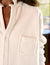 Close-up of a person wearing the FRANK & EILEEN "EILEEN Relaxed Button Up" in Triple Fleece Vintage White, featuring bust-flattering button placement and frayed edges, with a small pocket on the left side. The slightly turned-up collar highlights its relaxed fit against a softly blurred background.