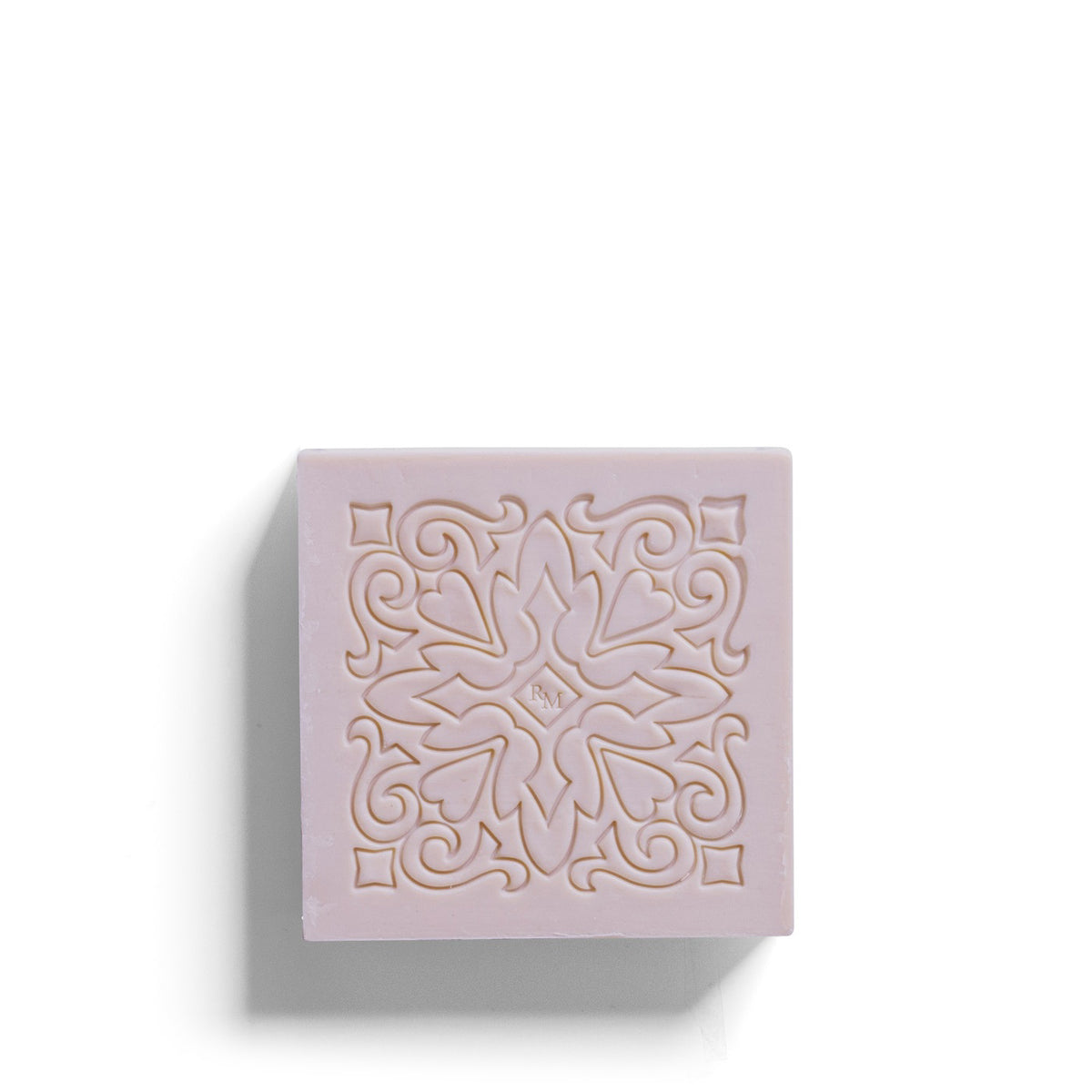 The ROSE ET MARIUS - SUNLIT ROSE WATER SCENTED SOAP GIFT BOX features a pastel pink square soap bar with an ornate, symmetrical floral design and carved swirls, displayed on a white background with shadows to the left and bottom.