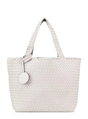 The WOVEN REVERSIBLE TOTE BAG by LINES OF DENMARK is a white tote featuring two shoulder straps and a circular faux-leather tag on one strap. This shopper showcases a textured, interlaced pattern and reversible design, providing stylish and elegant dual styling options. The image background is plain white.