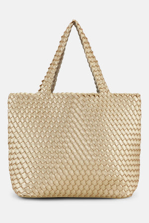 The WOVEN REVERSIBLE TOTE BAG by LINES OF DENMARK is a white tote featuring two shoulder straps and a circular faux-leather tag on one strap. This shopper showcases a textured, interlaced pattern and reversible design, providing stylish and elegant dual styling options. The image background is plain white.