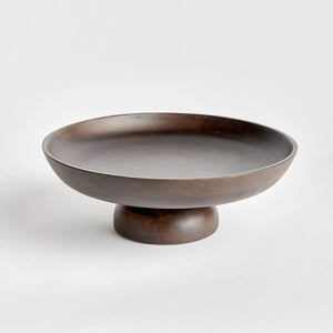 The BOWIE FOOTED BOWL by NAPA HOME AND GARDEN stands against a plain white background. Crafted from dark brown mango wood, its wide, shallow basin features smooth, curved edges and a polished finish that highlight the contemporary design's craftsmanship. The bowl rests on a solid, rounded base providing stability.