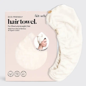 The QUICK DRY HAIR TOWEL by KITSCH is packaged in a cream-colored box, detailed with a black droplet shape and an inset image of someone wearing the highly absorbent towel. Designed for fine, curly, or straight hair, it's crafted from organic cotton and bamboo. The text and icons on the packaging are clearly visible.