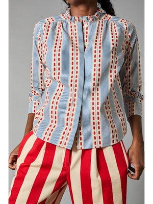 A person with long hair faces away, showcasing the HOPE FOR FLOWERS Frilled Cuff Shirt made from organic cotton, featuring blue and red stripes with dots, paired stylishly with eco-friendly red and white striped pants.