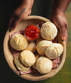 The cookbook cover titled "When Southern Women Cook Luncheon" by FEARRINGTON VILLAGE showcases hands preparing biscuits. One hand holds a biscuit cutter, while the other holds a bowl of biscuits, butter, and jam. The text details include the foreword by Toni Tipton-Martin and editing by Morgan Bolling from America's Test Kitchen.