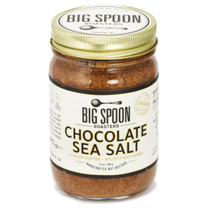 A jar of Big Spoon Roasters Chocolate Sea Salt Almond Wildflower Nut Butter, crafted using heirloom Mission variety almonds and wildflower honey. The jar features a gold lid and a white label with black text and graphics, showcasing the brand name and details of the contents.