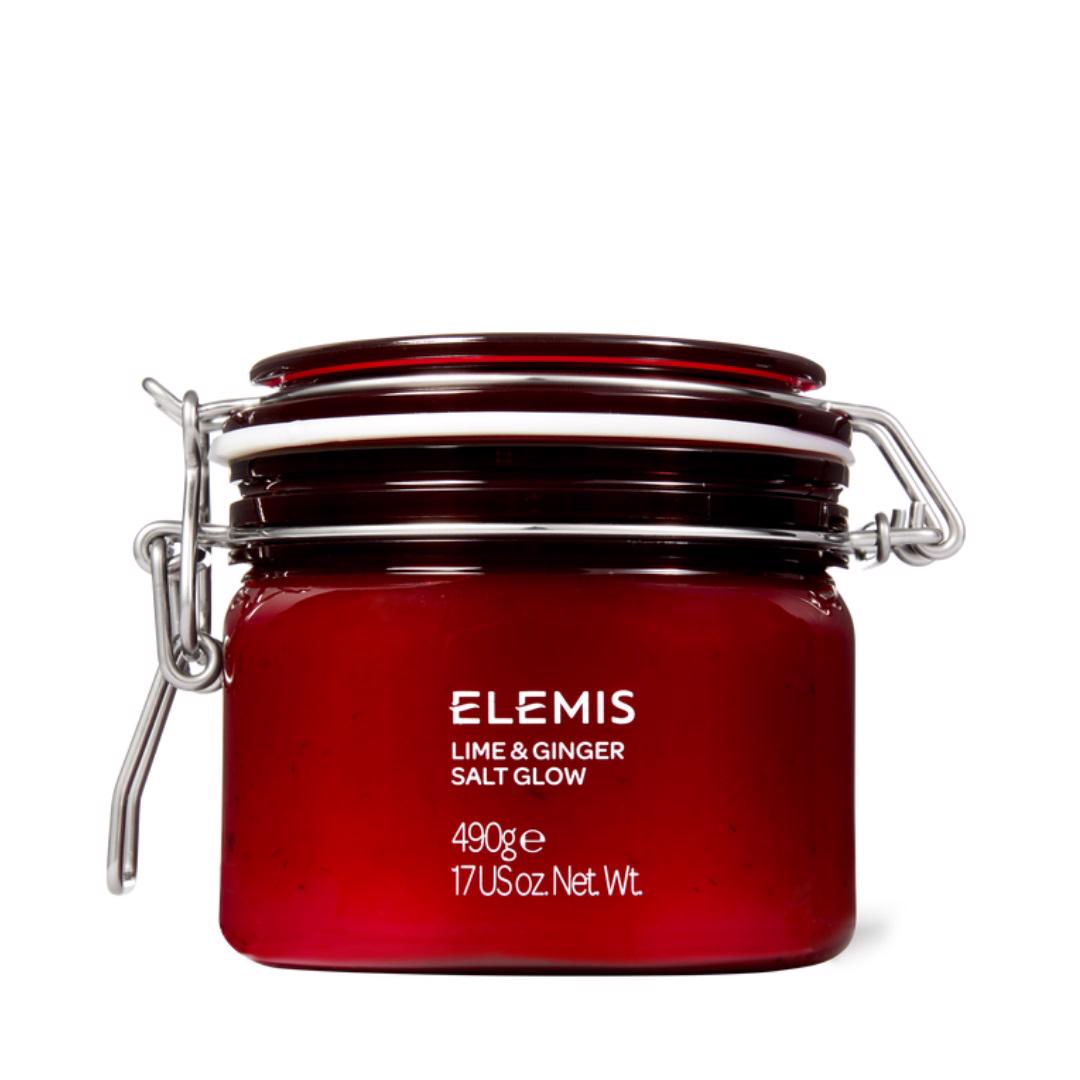 A red glass jar with a clasp lid is labeled &quot;ELEMIS - EXOTIC LIME &amp; GINGER SALT GLOW&quot; from the brand ELEMIS - STEINER. The text indicates it weighs 490 grams or 17 US ounces. This salt scrub exfoliates and moisturizes the skin, and the jar is displayed against a white background.