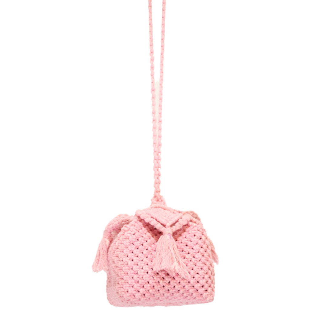The PANDORA ROSAMUND BOX BAG by BRUNNA CO. is a small, handmade pink crocheted bag with a long strap and two decorative tassels hanging from the flap. Crafted from hand-dyed pure cotton, this bag features a textured, chunky knit pattern and a simple, charming design, making it perfect for those who appreciate sustainable fashion accessories.