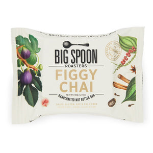 The image displays the packaging of a "BIG SPOON ROASTERS - FIGGY CHAI NUT BUTTER SNACK BAR." The white wrapper is adorned with illustrations of figs, spices, and nuts, emphasizing that it contains gluten-free whole grains and non-GMO pea protein. Additionally, it is free from dairy, gluten, soy, and palm oil, with a weight of 60g (2.1oz).