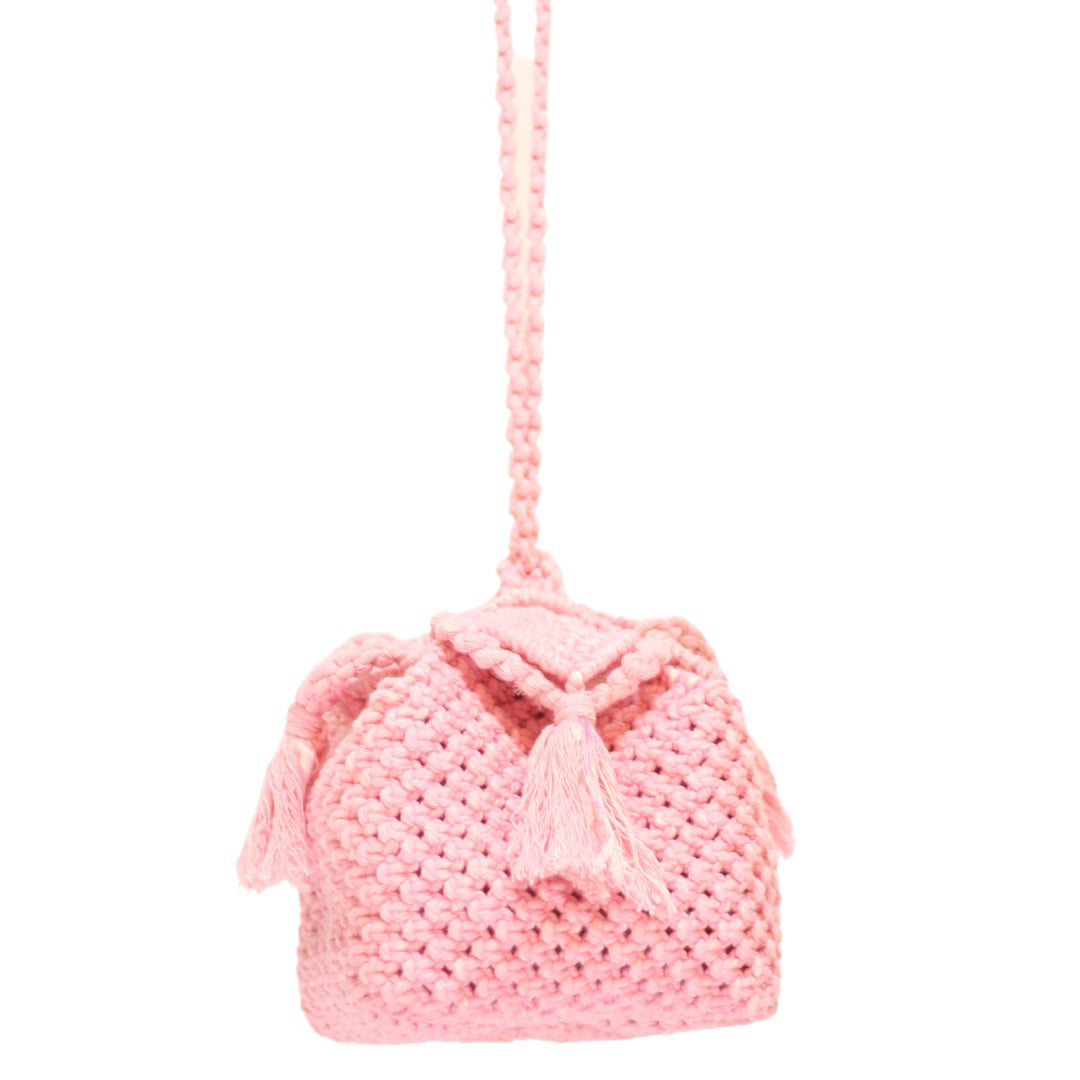 The PANDORA ROSAMUND BOX BAG by BRUNNA CO. is a small, handmade pink crocheted bag with a long strap and two decorative tassels hanging from the flap. Crafted from hand-dyed pure cotton, this bag features a textured, chunky knit pattern and a simple, charming design, making it perfect for those who appreciate sustainable fashion accessories.