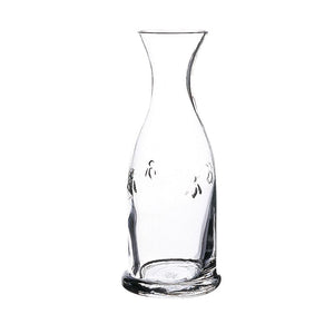 The BEE CARAFE TALL by LA ROCHERE is a tall, clear glass carafe with a narrow neck and wide base, adorned with subtle floral engravings. It is dishwasher safe and boasts a simple and elegant design, making it perfect for serving beverages.