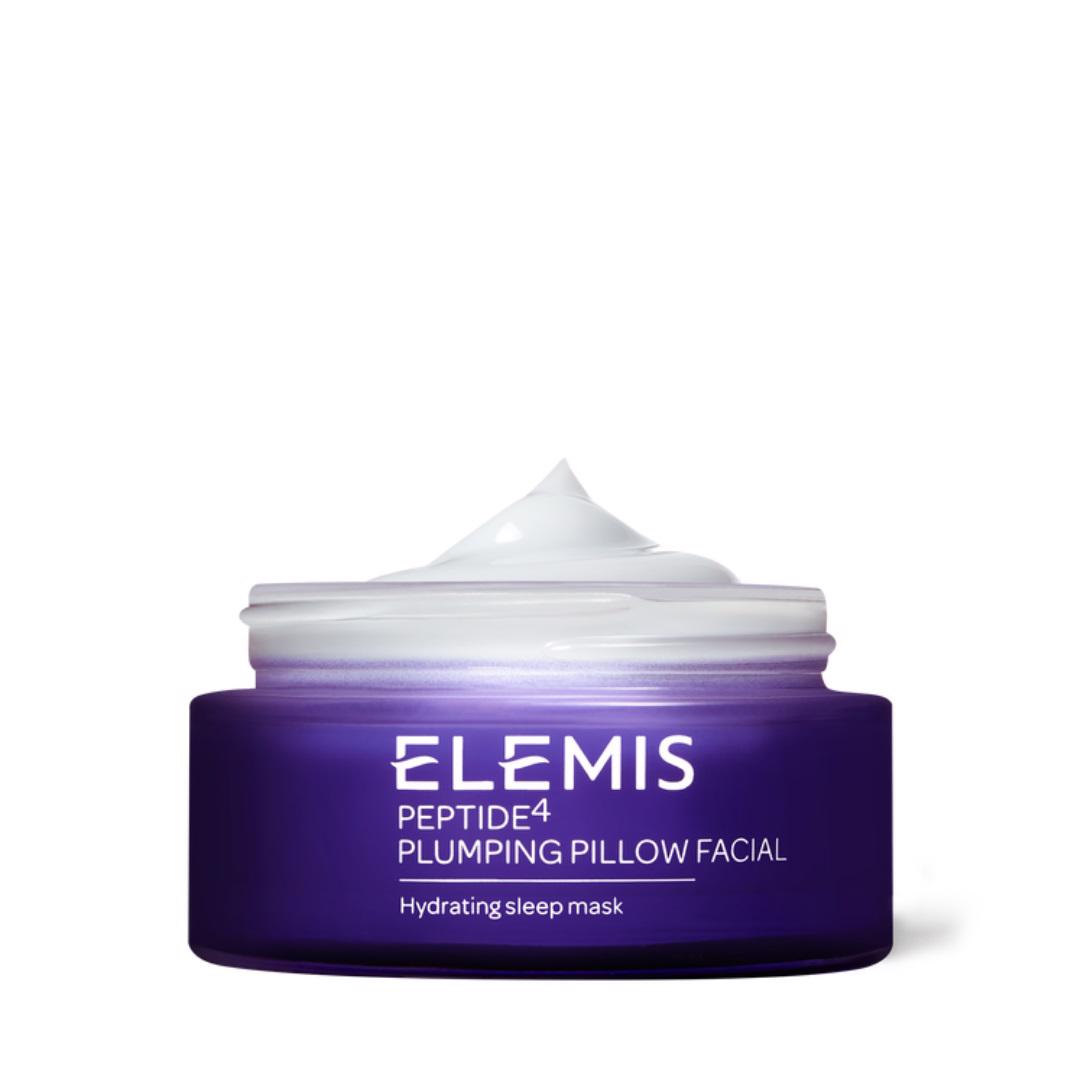 A jar of ELEMIS - PEPTIDE4 PLUMPING PILLOW FACIAL by ELEMIS - STEINER is shown with its lid off, revealing a swirl of the creamy overnight moisture mask inside. The purple jar features white text, indicating it is a hydrating sleep mask designed for a radiant complexion.