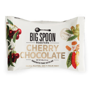 A white package of the Big Spoon Roasters Cherry Chocolate Peanut Snack Bar handcrafted with organic small-batch Askinosie dark chocolate. The wrapper features images of cherries and cocoa beans, highlighting that the bar is dairy, gluten, soy, and palm oil free. The net weight is 60g (2.1 oz).