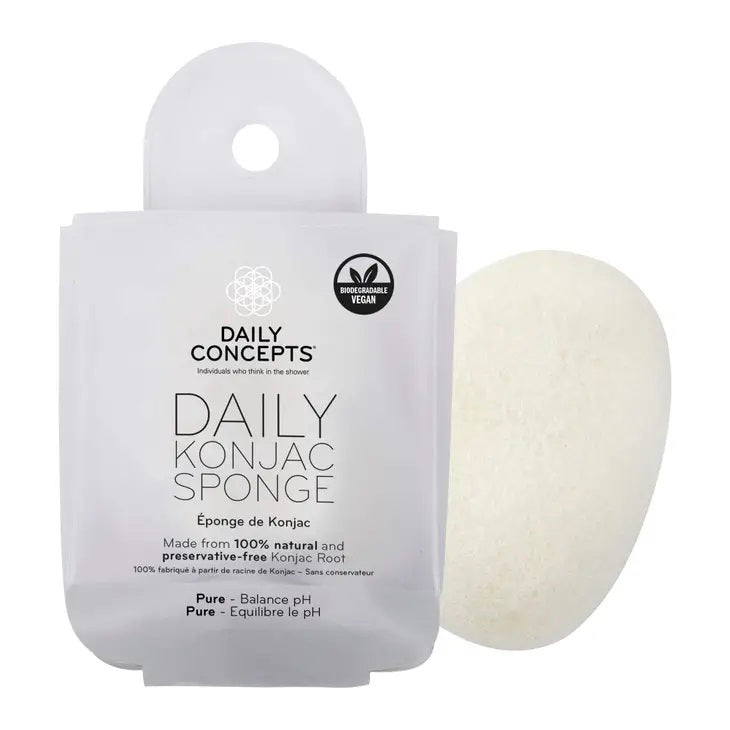 A white, teardrop-shaped Daily Concepts Konjac Sponge - Pure is displayed next to its transparent, branded packaging. The packaging emphasizes its eco-friendly and vegan features, along with its 100% natural and preservative-free Konjac root composition for a gentle skin cleanse inspired by Japanese beauty traditions.
