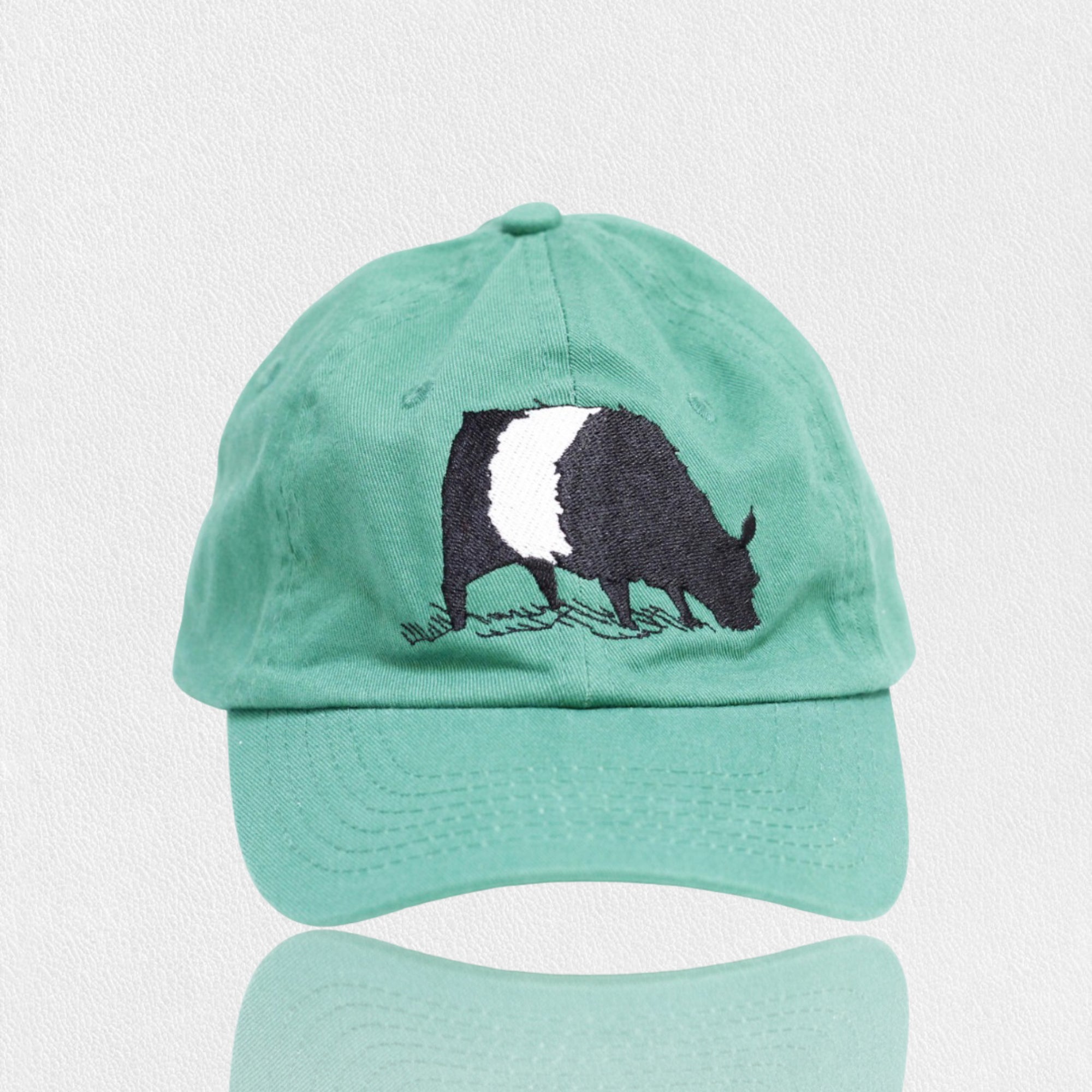 The FEARRINGTON LIFESTYLE COLLECTION - YOUTH BELTIE TWILL HAT from VALUCAP THREDS is a blue cotton twill baseball cap featuring an embroidered black and white badger on the front. This premium fabric cap has a curved brim and is displayed against a plain, white background.